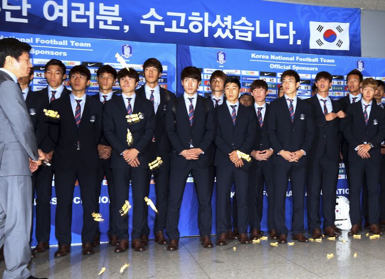 En esta foto del 30 de junio de 2014, los jugadores de la selecci&oacute;n surcoreana observan a un grupo de hinchas que les lanzan dulces tradicionales, un insulto, a su regreso del Mundial, en el que fueron eliminados en la primera fase (AP Foto/Yonhap,
