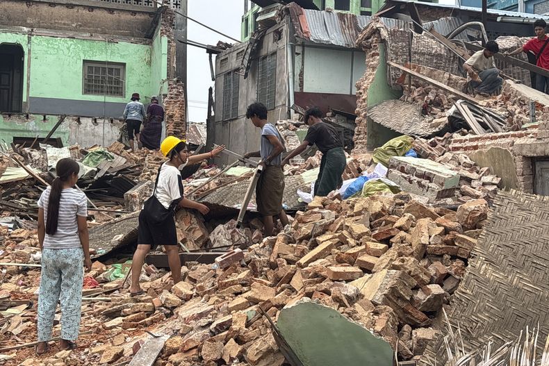 Gente limpia restos de edificios dañados tras un sismo el 28 de marzo, en Naipyidó, Myanmar, el lunes 7 de abril de 2025. (AP Foto)