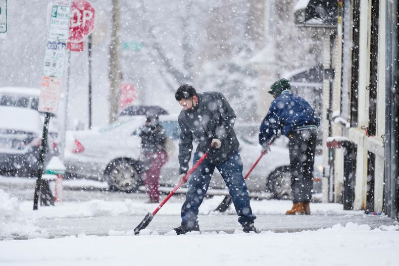 ARCHIVO - Personas limpian una acera durante una tormenta de nieve en Filadelfia, el 13 de febrero de 2024. (AP Foto/Matt Rourke, Archivo)
