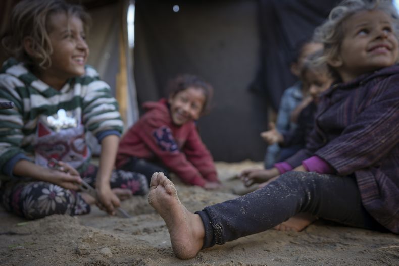 Los nietos de Reda Abu Zarada, desplazados de Jabaliya en el norte de Gaza, juegan cerca de su casa de campaña en Jan Yunis, Franja de Gaza, el 19 de diciembre de 2024. (AP Foto/Abdel Kareem Hana)