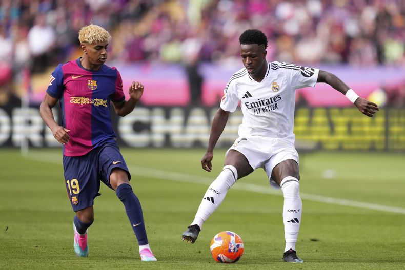 Vinicius Júnior (derecha) del Real Madrid y Lamine Yamal del Barcelona pugnan por el balón en el partido de la Liga española, el domingo 11 de mayo de 2025, en Barcelona. (AP Foto/José Bretón)