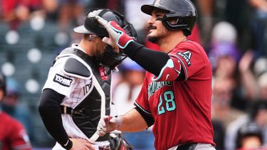El pelotero de los Diamondbacks de Arizona, Nolan Arenado (frente), hace gestos mientras cruza el plato tras conectar un cuadrangular de dos carreras, mientras el receptor de los Rockies de Colorado, Brett Sullivan, espera que se reanude el juego en la primera entrada de un partido de béisbol, el jueves 24 de septiembre de 2026, en Denver. (Foto AP/David Zalubowski)