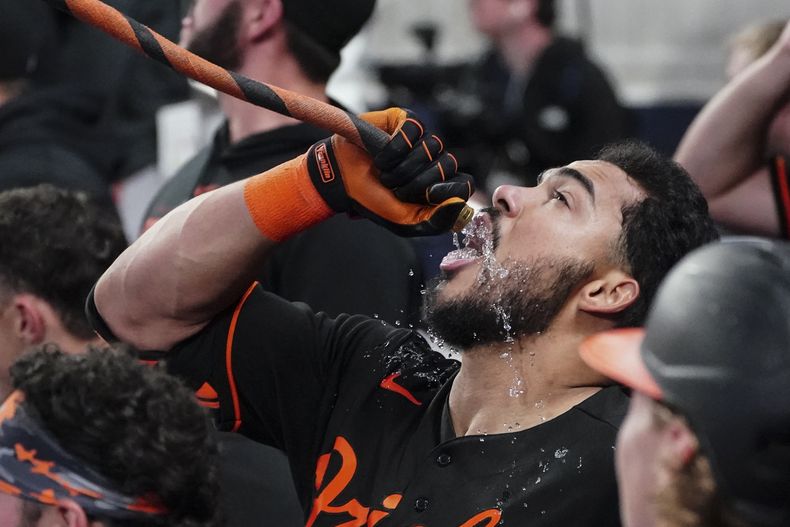 El venezolano Anthony Santander, de los Orioles de Baltimore, bebe agua de una manguera tras conectar un grand slam en el encuentro del viernes 5 de mayo de 2023, ante los Bravos de Atlanta (AP Foto/John Bazemore)