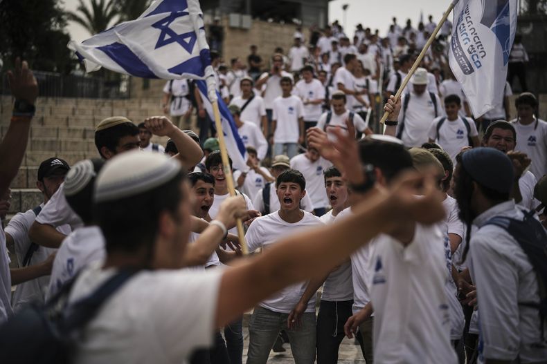 Israelíes ondean banderas nacionales durante una marcha por el Día de Jerusalén, una festividad israelí que celebra la captura de Jerusalén del este en la guerra de Oriente Medio de 1967, en la Ciudad Vieja de Jerusalén, el lunes 26 de mayo de 2025. (AP Foto/Leo Correa)