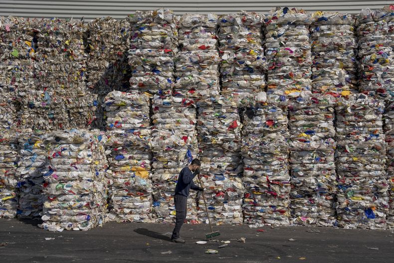 Un empleado de una planta de reciclaje GreenNet limpia el piso junto a grandes pilas de plástico desechable listas para su exportación, el 25 de enero de 2023, en la zona industrial Atarot, al norte de Jerusalén. (AP Foto/Oded Balilty, Archivo)