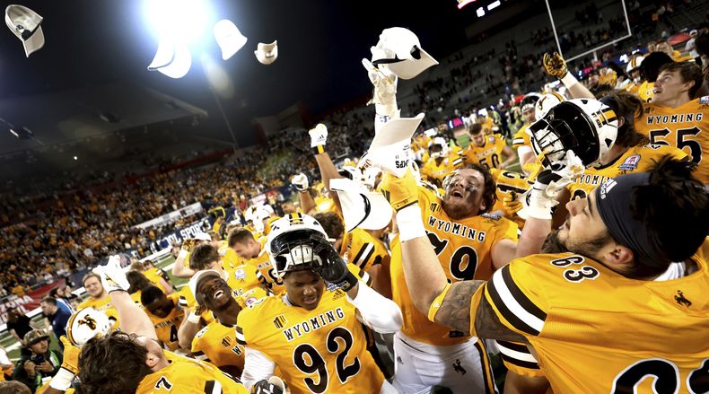 Los jugadores de Wyoming celebran con gorras de campeonato después de derrotar a Toledo durante el partido de fútbol americano universitario de la NCAA Arizona Bowl el sábado 30 de diciembre de 2023 en Tucson, Arizona (Kelly Presnell/Arizona Daily Star vía AP)