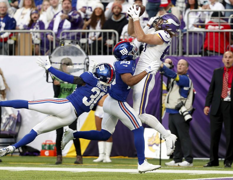 El tight end de los Vikings de Minnesota T.J. Hockenson atrapa un pase de touchdown de 15 yardas por encima del safety de los Giants de Nueva York Julian Love y el cornerback Darnay Holmes, en la segunda mitad del partido del 24 de diciembre de 2022, en Minneapolis. (AP Foto/Bruce Kluckhohn, Archivo)