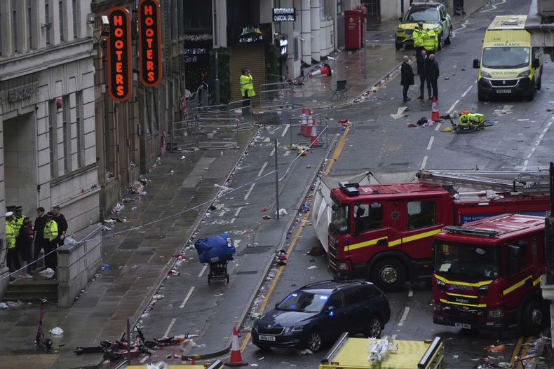 Aficionados abandonan el sitio tras la llegada de la policía y el personal de emergencia después de que un auto embistiera a peatones cerca del Edificio Liver durante el desfile de los campeones de la Premier League en Liverpool, Inglaterra, el lunes 26 de mayo de 2025. (AP Foto/Jon Super)