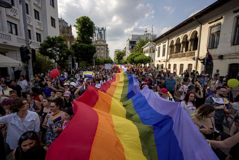 Varias personas sostienen una bandera de arcoíris durante un desfile del Orgullo Gay en Bucarest, Rumania, el sábado 7 de junio de 2025. (AP Foto/Andreea Alexandru)