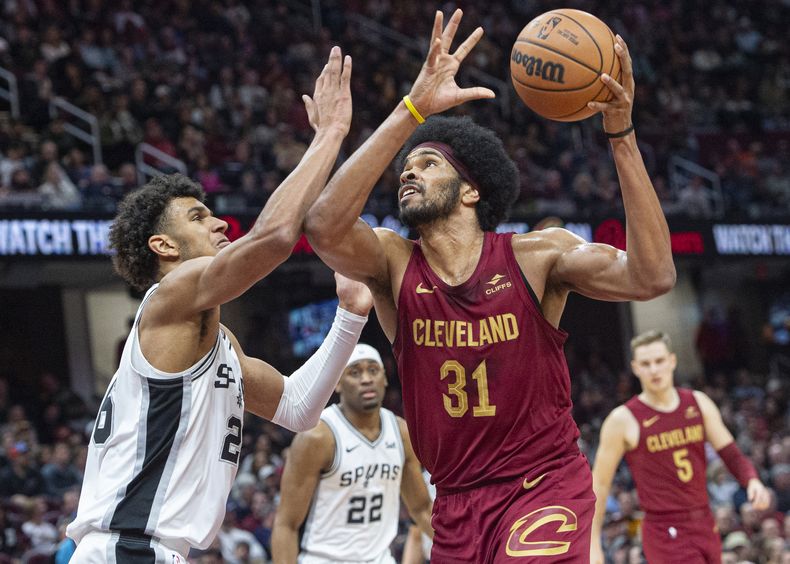 Jarrett Allen (31), de los Cavaliers de Cleveland, ataca la canasta frente la marca defensiva de Dominick Barlow, izquierda, de los Spurs de San Antonio, durante la segunda mitad del juego de baloncesto de la NBA en Cleveland, el domingo 7 de enero de 2024. (AP Foto/Phil Long)