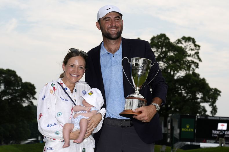 Scottie Scheffler (derecha) posa junto a su hijo bebé Bennett y su esposa Meredith luego de ganar el torneo de golf Travelers Championship en TPC River Highlands, el domingo 23 de junio de 2024, en Cromwell, Connecticut. (AP Foto/Seth Wenig)