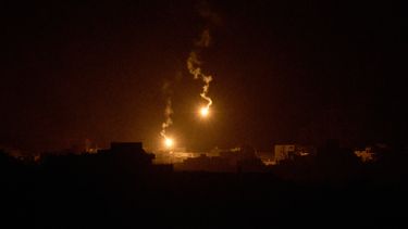 Bengalas lanzadas por el ejército israelí iluminan edificios destruidos en su campaña terrestre y aérea en el norte de la Franja de Gaza, vistas desde el sur de Israel, el 24 de septiembre de 2025. (AP Foto/Leo Correa)
