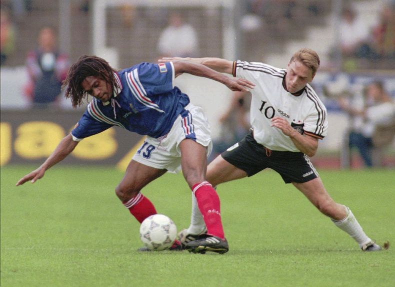 ARCHIVO - Christian Karembeu de Francia, a la izquierda, protege el balón durante el partido internacional de fútbol entre Alemania y Francia en Stuttgart, Alemania, el sábado 1 de junio de 1996. El ex futbolista internacional Christian Karembeu, ganador de la Copa del Mundo de 1998 y de la Eurocopa 2000 con Francia, reveló que dos de sus familiares murieron durante los disturbios en el territorio francés de Nueva Caledonia, en el Pacífico, que han dejado siete muertos. (AP Foto/Thomas Kienzle, Archivo)
