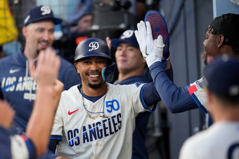 El pelotero de los Dodgers de Los Ángeles, Mookie Betts, es felicitado por sus compañeros en la cueva tras anotar con un doblete de Kyle Tucker durante la primera entrada de un partido de béisbol contra los Gigantes de San Francisco, el sábado 19 de septiembre de 2026, en Los Ángeles. (Foto AP/Mark J. Terrill)
