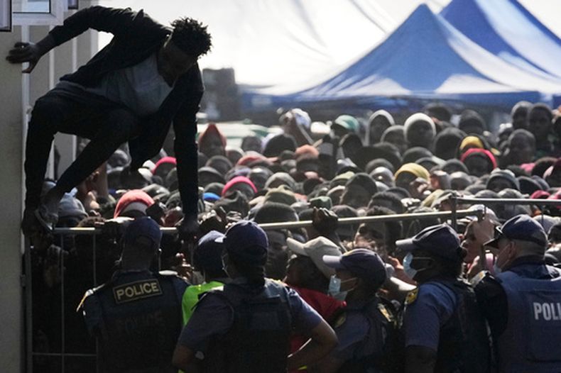 ARCHIVO - Un migrante de Malaui salta una barricada mientras la policía gestiona la fila para su deportación en un centro de detención temporal en Durban, Sudáfrica, el jueves 18 de junio de 2026. (AP Foto/Themba Hadebe, Archivo)