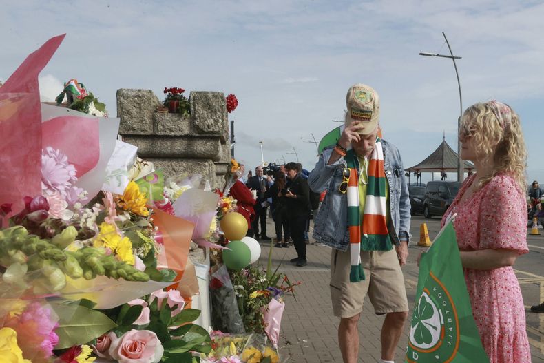 personas miran ofrendas colocadas fuera de la antigua casa de Sinéad OConnor antes del funeral de la cantante en Bray en el condado de Wicklow, Irlanda el martes 8 de agosto de 2023. (Liam McBurneyPA vía AP)