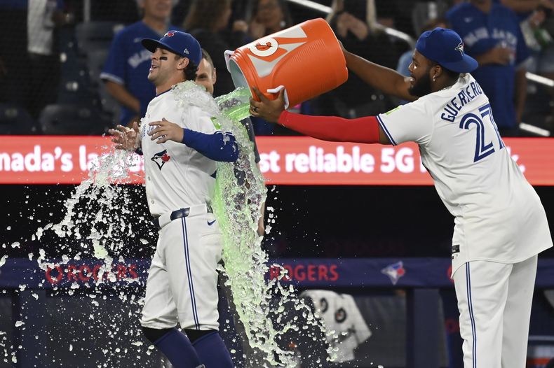 Ernie Clement es empapado por el dominicano Vladimir Guerrero Jr., su compañero en los Azulejos de toronto, tras la victoria sobre los Angelinos de Los Ángeles, el jueves 22 de agosto de 2024 (Jon Blacker/The Canadian Press via AP)