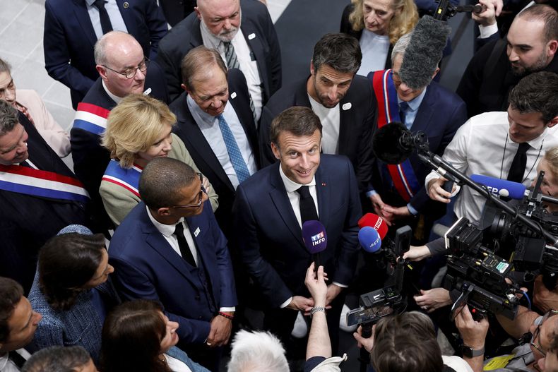 El presidente francés Emmanuel Macron (cent) habla con periodistas en la inauguración de un centro acuático para las venideras olimpiadas, en Saint-Denis, cerca de París, el 4 de abril de 2024. (Gonzalo Fuentes/Pool via AP)