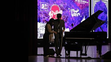Imlibenla Jamir, de 30 años, a la izquierda, guía a su hermano Takosangba Pongen, de 27 años, un pianista ciego, al escenario para su actuación en el Festival de Piano Brillante de dos días en Bengaluru, India, el domingo 29 de septiembre de 2024. (Foto AP/Aijaz Rahi)
