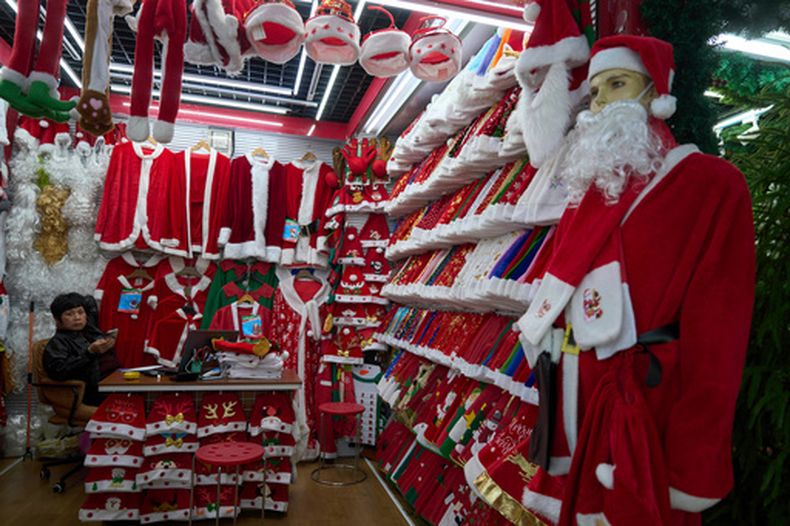 ARCHIVO - Una persona espera a clientes junto a disfraces de Santa Claus en el Mercado Internacional Yiwu en Yiwu, en la provincia oriental china de Zhejiang, el 10 de abril de 2025. (AP Foto/Ng Han Guan, Archivo)