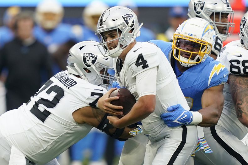 El quarterback Aidan OConnell (4), de los Raiders de Las Vegas, es capturado por el linebacker Khalil Mack, derecha, de los Chargers de Los Ángeles, durante la segunda mitad del juego de la NFL, el domingo 1 de octubre de 2023, en Inglewood, California. (AP Foto/Ryan Sun)