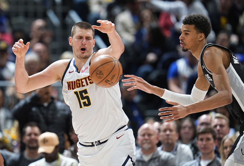 El centro de los Nuggets de Denver Nikola Jokic (izquierda) el pívot de los Spurs de San Antonio Victor Wembanyama disputan la pelota durante la segunda mitad del juego de baloncesto de la NBA, el martes 2 de abril de 2024, en Denver. (AP Foto/David Zalubowski)