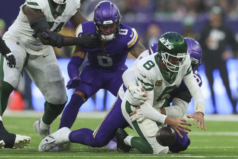 Aaron Rodgers (8), derecha, quarterback de los Jets de Nueva York, es capturado por Harrison Phillips, de los Vikings de Minnesota, durante la segunda mitad del juego de la NFL, el domingo 6 de octubre de 2024, en el estadio del Tottenham Hotspur, en Londres. (AP Foto/Ian Walton)