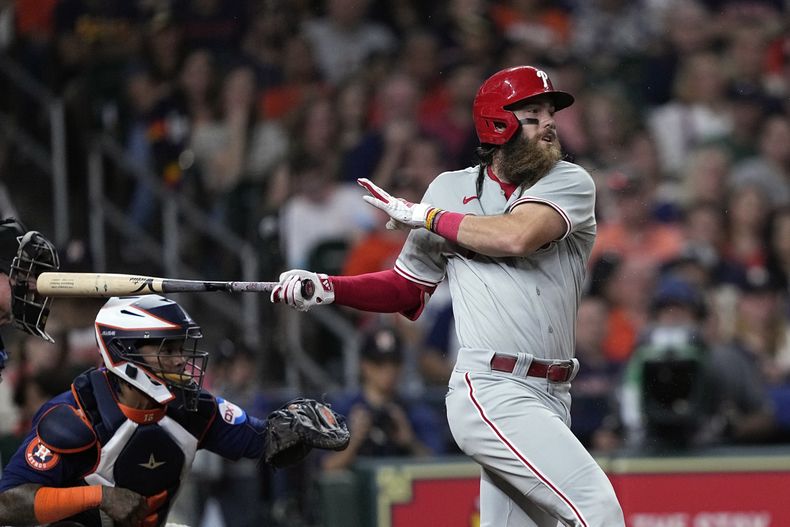 Brandon Marsh, derecha, de los Filis de Filadelfia, pega sencillo productor mientras el receptor de los Astros de Houston, Martin Maldonado, se queda esperando el lanzamiento durante la séptima entrada del juego de béisbol, el viernes 28 de abril de 2023, en Houston. (AP Foto/David J. Phillip)