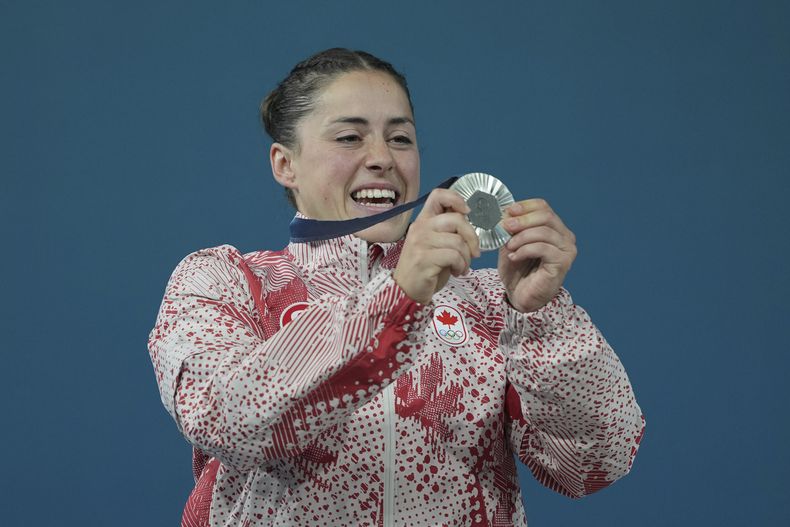 La canadiense Maude Charon celebra su medalla de plata en el podio tras la competencia de 59 kg de halterofilia de los Juegos Olímpicos, el jueves 8 de agosto de 2024, en París. (AP Foto/Kin Cheung)
