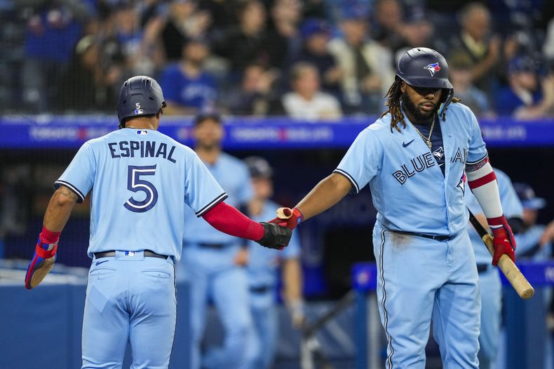 Santiago Espinal (5) de los Azulejos de Toronto celebra con su compañero Vladimir Guerrero Jr. (27) tras anotar una carrera ante los Medias Blancas de Chicago, el miércoles 26 de abril de 2023, en Toronto. (Andrew Lahodynskyj/The Canadian Press vía AP)