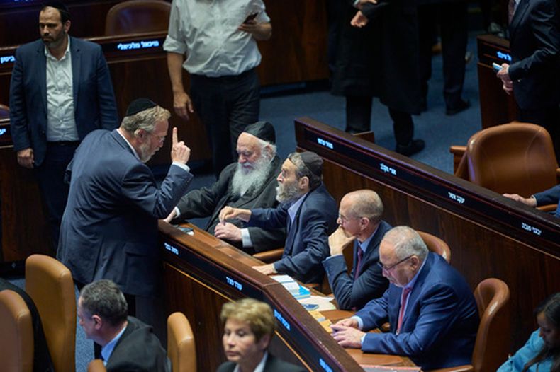 Legisladores en el Parlamento israelí discuten tras la votación de un proyecto de ley que busca igualar el estudio de los textos judíos con el servicio militar, en Jerusalén, el lunes 13 de julio de 2026. (AP Foto/Ohad Zwigenberg)