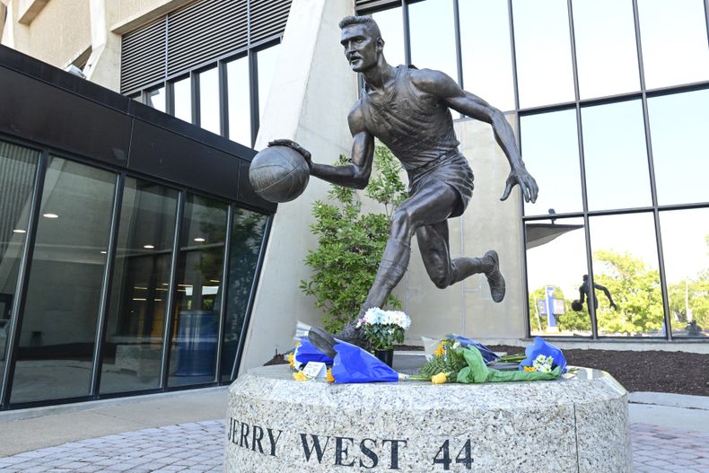 La foto del miércoles 12 de junio de 2024 muestra las ofrendas florales colocadas en la estatua de Jerry West en el Coliseum de Morgantown, Virginia Occidental (William Wotring/The Dominion-Post via AP)