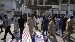 Musulmanes chiítas que salen de una mezquita después de las oraciones del viernes pisotean representaciones de las banderas estadounidense e israelí en repudio a los ataques aéreos israelíes a Gaza y solidaridad con los palestinos, en Islamabad, Pakistán, viernes 13 de octubre de 2023. (AP Foto/Anjum Naveed)