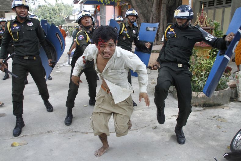 Un trabajador camboyano herido huye de la polic&iacute;a antimotines en el complejo de una pagoda budista en Phnom Penh, Camboya, el 12 de noviembre de 2013. (Foto AP