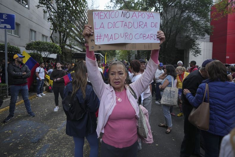 Una opositora del presidente venezolano Nicolás Maduro con un cartel que califica su gobierno de dictadura, en una protesta de respaldo a la oposición venezolana fuera de la embajada de ese país en Ciudad de México, el jueves 9 de enero de 2024, un día antes de la toma de posesión de Maduro para un tercer mandato. (AP Foto/Fernando Llano)