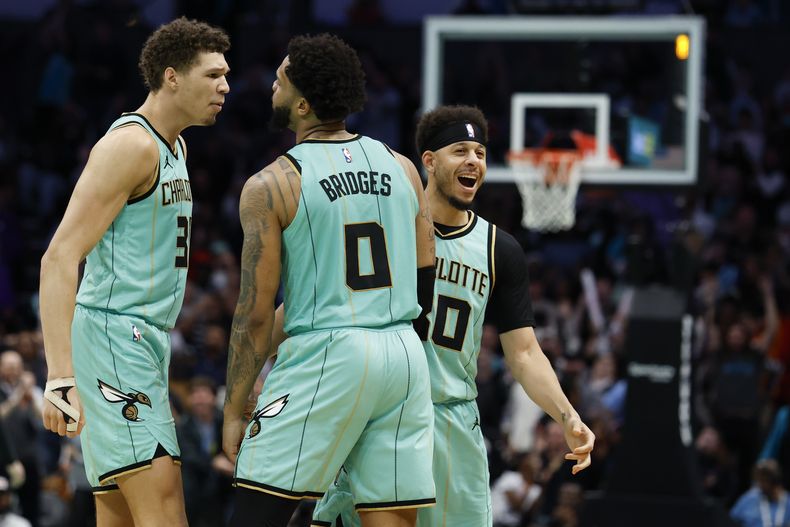 Miles Bridges (0), de los Hornets de Charlotte, celebra con Tidjane Salaun, izquierda, y guard Seth Curry, derecha, durante la segunda mitad del juego de baloncesto de la NBA en contra de los Spurs de San Antonio, el viernes 7 de febrero de 2025, en Charlotte, Carolina del Norte. (AP Foto/Nell Redmond)