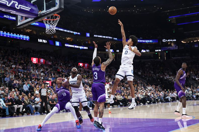 Jaylen Wells (0), de los Grizzlies de Memphis, dispara sobre Keyonte George (3), del Jazz de Utah, durante la primera mitad del juego de baloncesto de la NBA, el lunes 26 de octubre de 2026, en Salt Lake City. (AP Foto/Rob Gray)