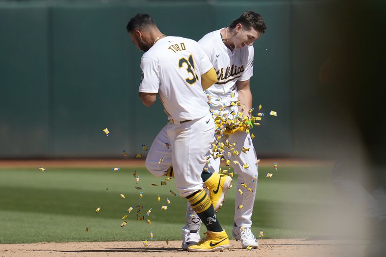 Tyler Soderstrom (derecha), de los Atléticos de Oakland, festeja con el venezolano Abraham Toro, luego de recibir un boleto con las bases llenas en la undécima entrada del encuentro ante los Rockies de Colorado, el jueves 23 de mayo de 2024 (AP Foto/Jeff Chiu)