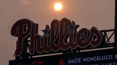 El Sol tiene un matiz anaranjado debido al humo proveniente de los incendios forestales de Canadá mientras se pone cerca de la pizarra de los Filis de Filadelfia durante la cuarta entrada de un partido de béisbol contra los Mets de Nueva York, el jueves 16 de julio de 2026, en Filadelfia. (Foto AP/Chris Szagola)