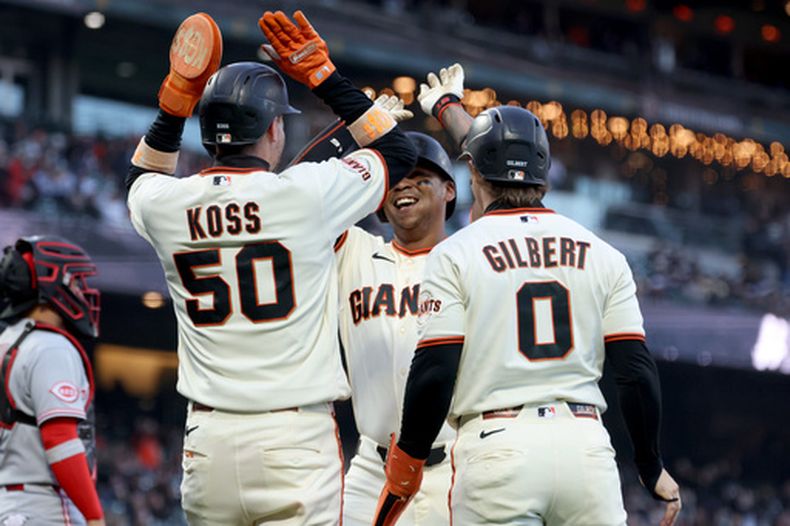 Rafael Devers, segundo desde la derecha, de los Gigantes de San Francisco, celebra con Christian Koss (50) y Drew Gilbert (0) después de batear un jonrón de tres carreras en el juego de béisbol de Grandes Ligas contra los Rojos de Cincinnati, durante la segunda entrada, el lunes 24 de agosto de 2026, en San Francisco. (AP Foto/Jed Jacobsohn)