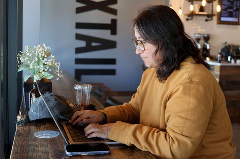 Lauren Contreras, de 40 años, trabaja desde su laptop en Foxtail Coffee Co., en Flagstaff, Arizona,el lunes 20 de abril de 2026. (AP Foto/Cheyanne Mumphrey)