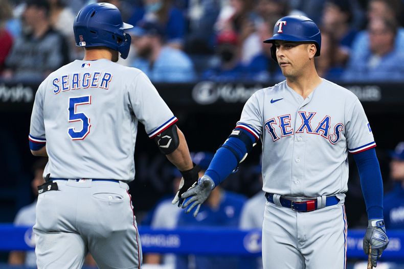 Corey Seager, de los Rangers de Texas, festeja su jonrón solitario con su compañero Nathaniel Lowe, en el juego del jueves 14 de septiembre de 2023, ante los Azulejos de Toronto (Spencer Colby/The Canadian Press via AP)