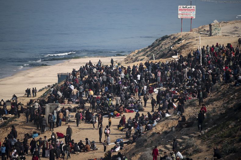 Palestinos desplazados se reúnen con sus pertenencias cerca de un control de carretera en la calle Al Rashid, mientras esperan regresar a sus hogares en la parte norte de la Franja de Gaza, el domingo 26 de enero de 2025, días después de que entrara en vigor el acuerdo de alto el fuego entre Israel y Hamas. (AP Foto/Jehad Alshrafi)