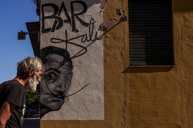 ARCHIVO - Un hombre pasa junto a un dibujo que representa al artista surrealista español Salvador Dalí durante un día caluroso y soleado en Madrid, España, el jueves 13 de julio de 2023. (Foto AP/Manu Fernandez, archivo)