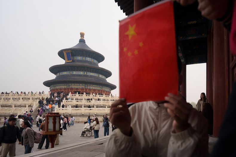 Un grupo de niños sostiene una bandera nacional china cerca del Salón de Oración por las Buenas Cosechas, en el Templo del Cielo en Beijing, China, el viernes 3 de abril de 2026. (Foto AP/Vincent Thian)