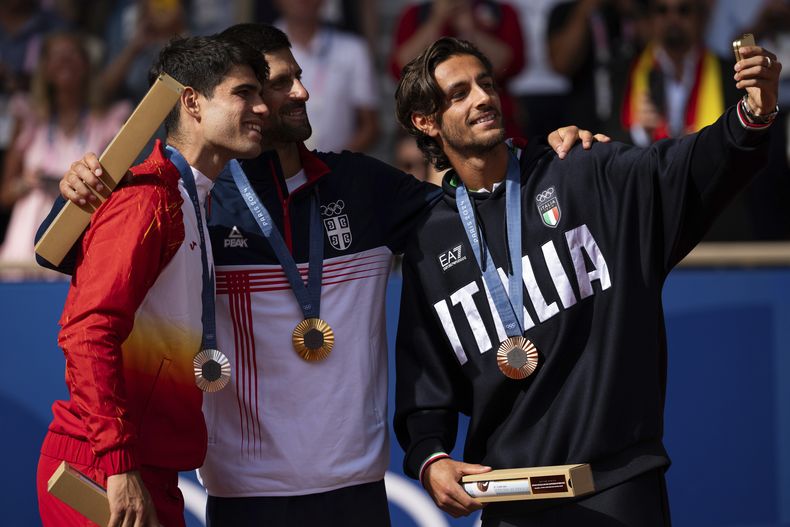 El serbio Novak Djokovic, ganador del oro olímpico, posa con Carlos Alcaraz, medallista de plata y Lorenzo Musetti, que ganó el bronce, en el torneo olímpico de París el domingo 4 de agosto del 2024. (AP Foto/Louise Delmotte)