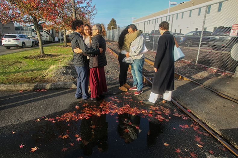 Inmigrantes de Portland, incluido Victor Cruz, en el centro a la derecha con la sudadera gris, abrazan a familiares tras ser liberados bajo fianza en Tacoma, Washington, el viernes 7 de noviembre de 2025. (AP Foto/Cedar Attanasio)