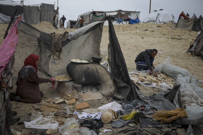 Mona Al-Zebda, desplazada de Ciudad de Gaza, hornea pan en un campamento de tiendas para palestinos desplazados en Muwasi, Rafah, sur de la Franja de Gaza, lunes 24 de febrero de 2025. (AP foto/Jehad Alshrafi)