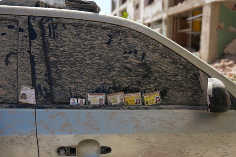 Familiares que buscan información en Catia La Mar, Venezuela, dejan tarjetas de identificación y fotografías de personas desaparecidas en la ventanilla de un auto cubierto de tierra el sábado 27 de junio de 2026, tres días después de que dos terremotos sacudieran el país. (AP Foto/Fernando Vergara)