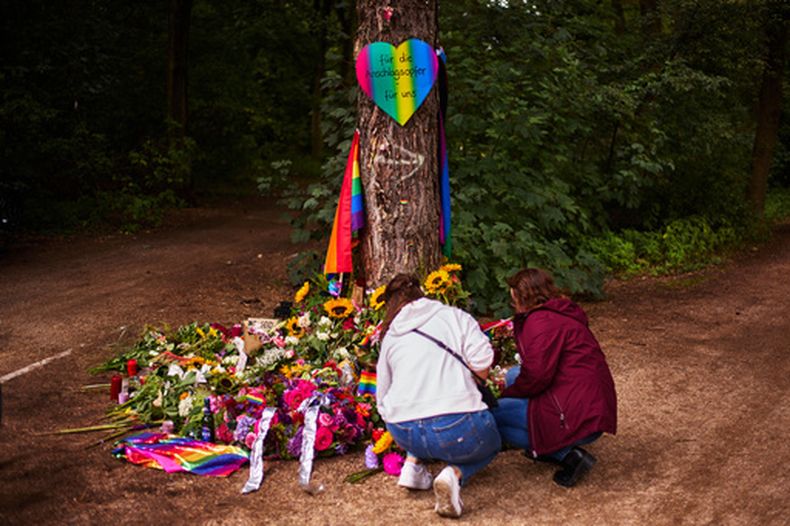 Dos mujeres depositan flores en un árbol de Tiergarten Park, cerca del sitio donde un hombre embistió con un auto a varias personas después del Desfile del Orgullo, realizado el sábado en Berlín, Alemania, el lunes 27 de julio de 2026. (AP Foto/Markus Schreiber)